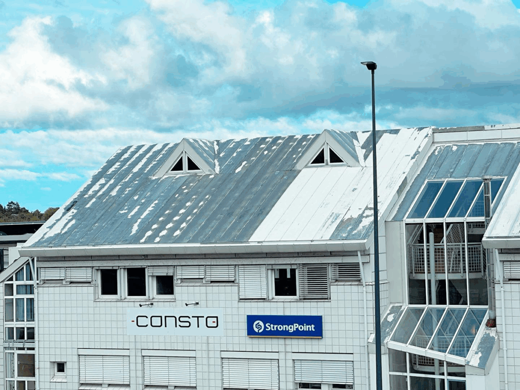 Hvit industribygg med falmet tak der malingen flasser av - før renovasjon