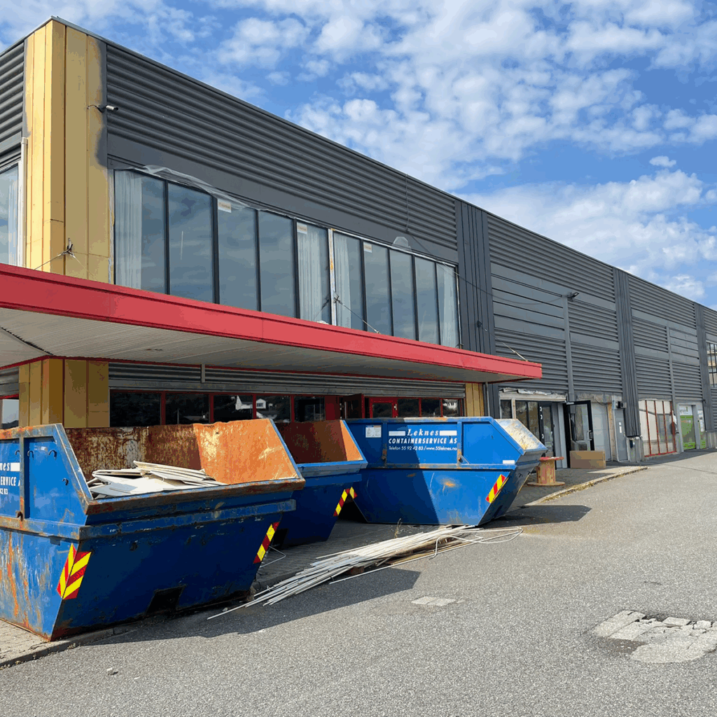 Metallfasade med vinduer på næringsbygg. Under arbeid. containere i forgrunn