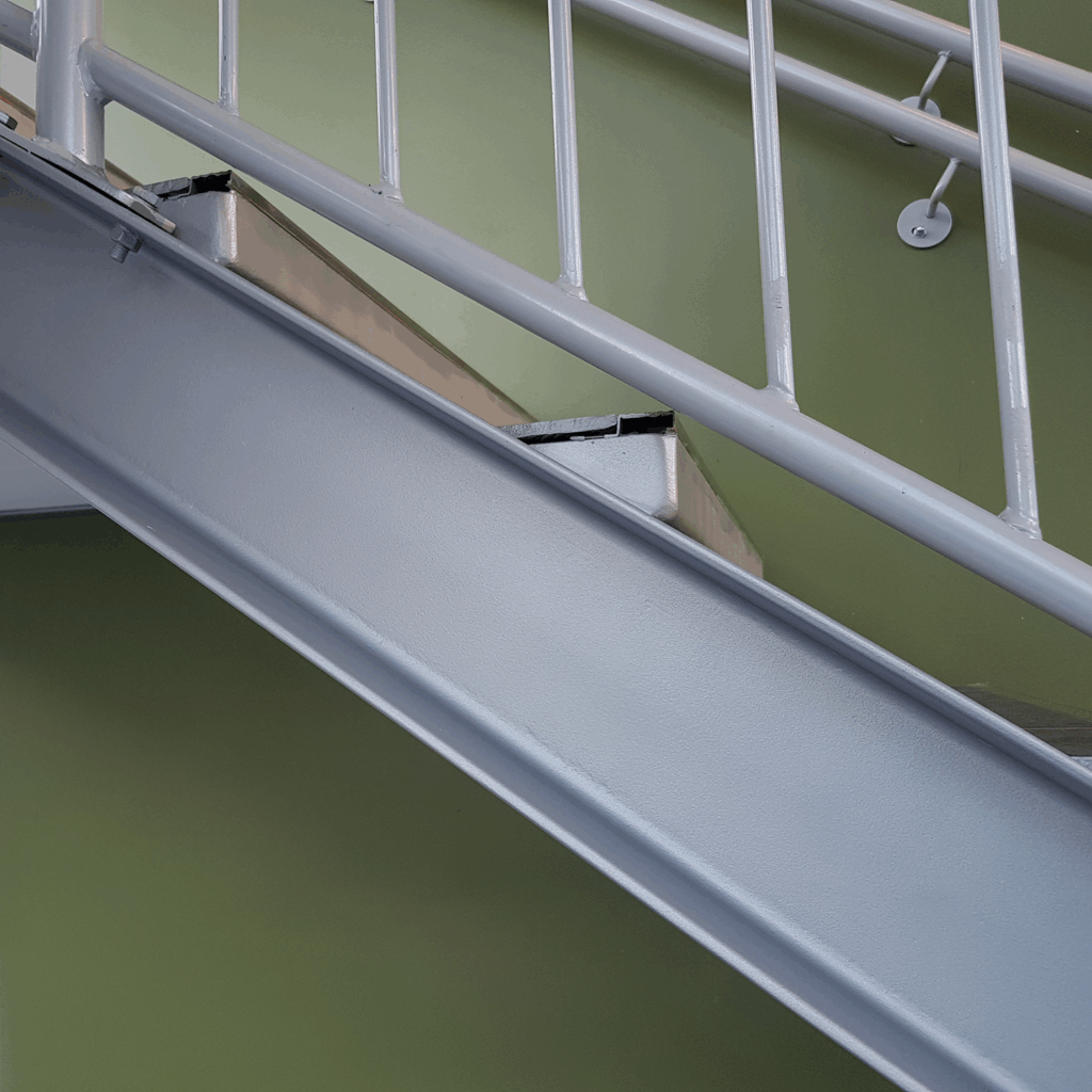 ståltrapp med stålrekkverk, nærbilde på siden hvor man ser stålbjelken som holder trinnene