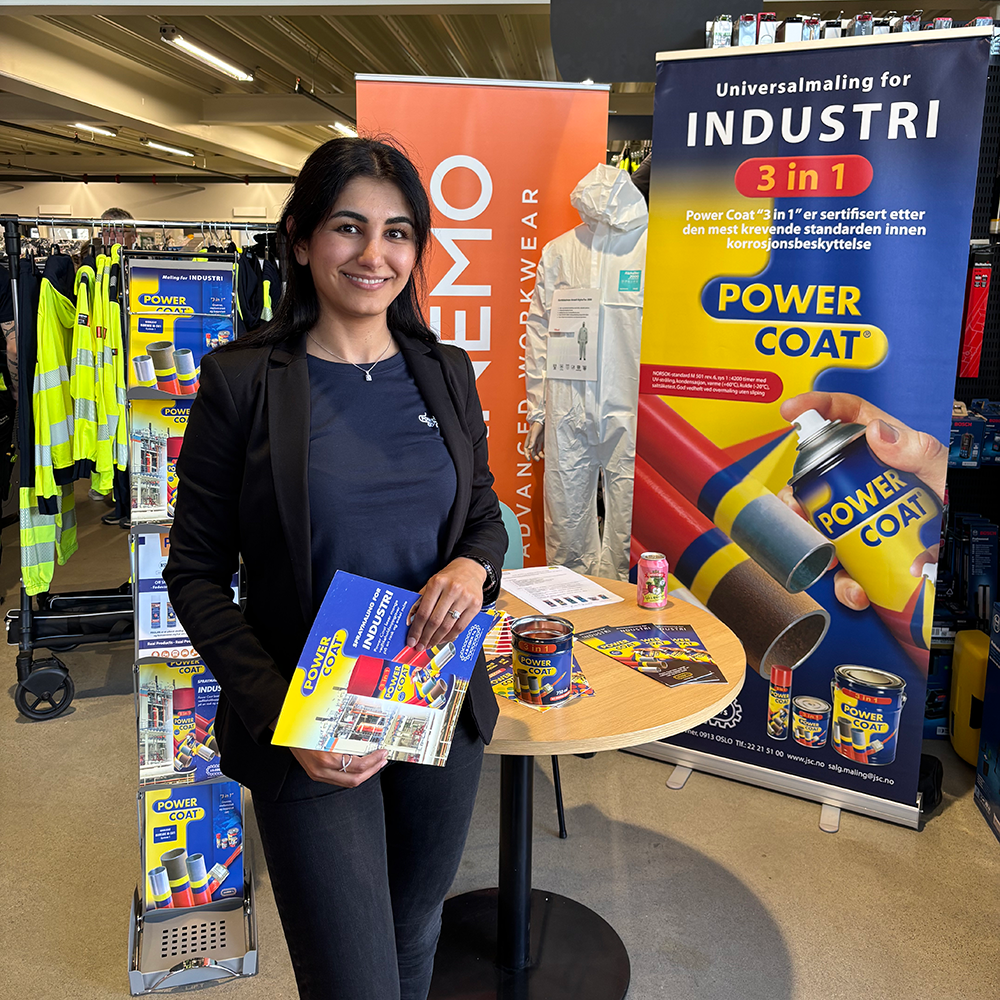 Kvinnelig selger som står ved salgsboden til Power Coat og presenterer en brosjyre