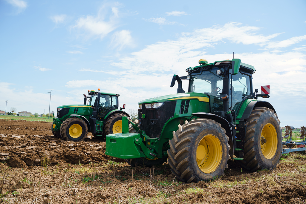 two green john deere tractors in front of picturesque rural landscape