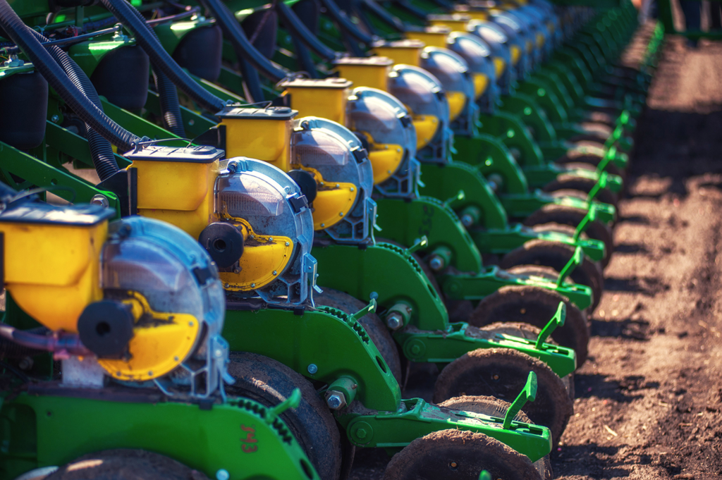 close up of more than ten green John Deere tractor plows in a neat row