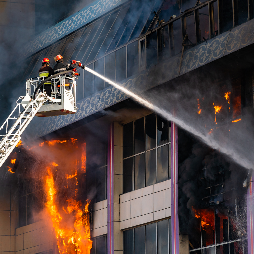 To brannmenn i en løftekrankurv retter brannslage mot brann i kontorbygg