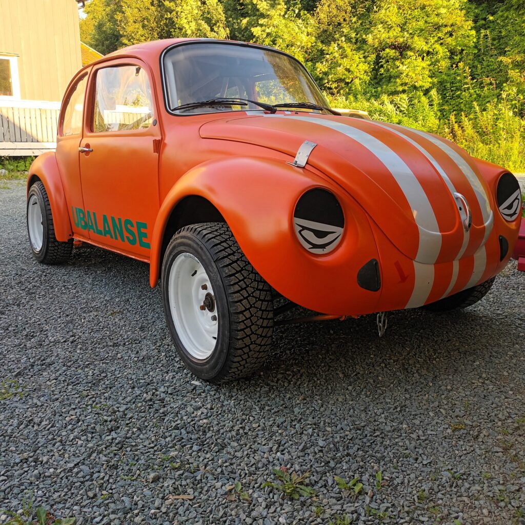 Sideansikt av en restaurert VW Boble, nå i oransje med hvite racing striper