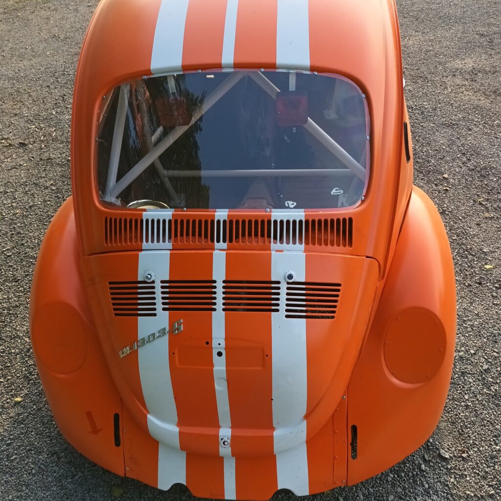 En restaurert VW Boble, nå i oransje med hvite racing striper, baksiden sett ovenifra.